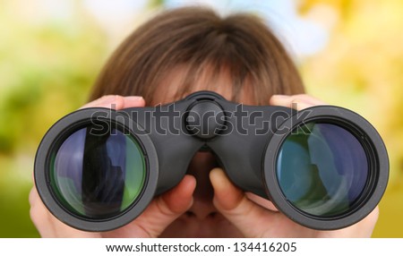 Black modern binoculars in hands on green background