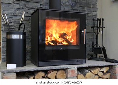 Black modern looking wood burning stove with logs underneath 
