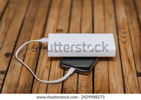 Black modern smartphone, a phone with a dead battery is charged with energy through a cable from a white power bank without electricity. Close-up photography, usb technology concept.