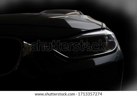 Black modern sport luxury car led xenon headlights - front view with black background in the garage