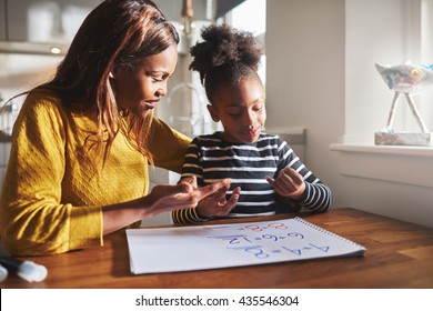 Black Mom And Child Doing Homework At Kitchen