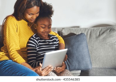Black mom and child with tablet having a good time smiling and learning