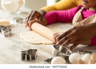 Black Mom And Daughter Rolling Up Dough For Cookies On Table In Kitchen, Baking At Home, Making Homemade Pastry Together, Caring Mother Teaching Little Girl Cooking, Cropped Image, Closeup