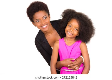 Black mother daughter posing happily with mom behind daughter holding arms around and both facing camera smiling