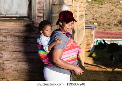 Black Mother With Her Daughter On Her Back While They Are In The Township