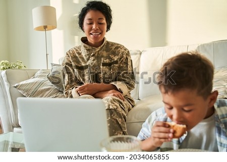 Black mother looking on son who is eating cupcake