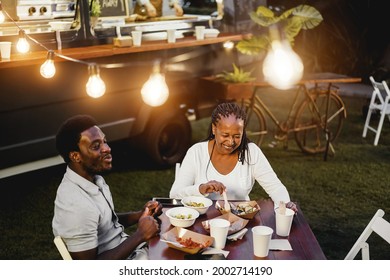 Black Mother And Son Eating And Drinking Healthy Food At Food Truck Restaurant Outdoor - Soft Focus On Senior Woman Face