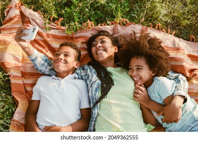 Black mother taking selfie photo with her two son during picnic on summer field - Powered by Shutterstock