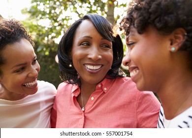 Black Mother And Two Adult Daughters In Garden, Close Up