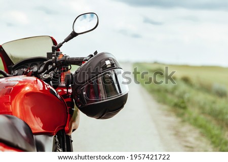 Black motorcycle helmet hanging on the handlebars of the motorcycle