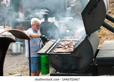 Black Mountain, NC / USA - August 10, 2008:  Older Man Outside Grilling Ribs At A Local Fair In Black Mountain, NC Showing The Extra Large Grill.