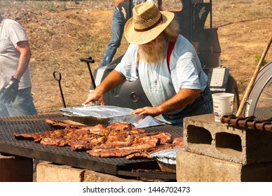 Black Mountain, NC / USA - August 10, 2008:  Older Man Outside Grilling Ribs At A Local Fair In Black Mountain, NC Showing The Extra Large Grill.