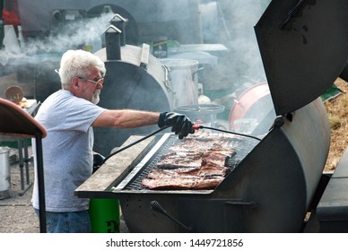 Black Mountain, NC / USA - August 10, 2008:  Older Man Outside Grilling Ribs At A Local Fair In Black Mountain, NC Showing The Extra Large Grill.