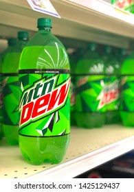 Black Mountain, NC / USA - June 14, 2019: Creative photo of a Mountain Dew 2 liter bottle alone on the shelf with other bottles blurred in the background.