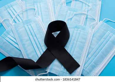 Black Mourning Ribbon On The Background Of Medical Masks. Death Concept From Coronavirus COVID-19