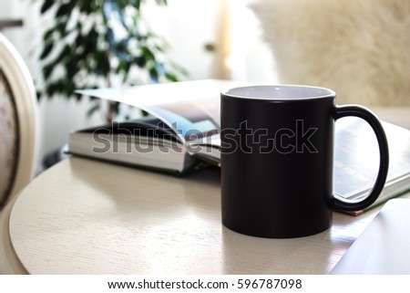 Black mug, cup on a table with book, Mockup