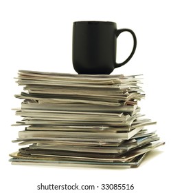 Black mug sits atop a stack of magazines