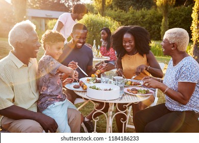 Black Multi Generation Family Eating At A Table In Garden