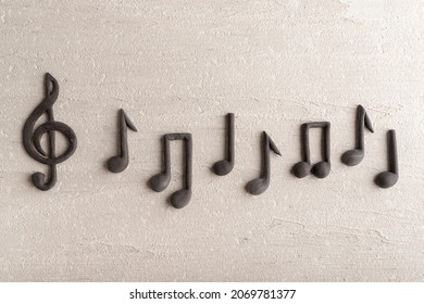 Black music violin clef sign and note on rough beige surface. G-clef. Treble clef. Close up.