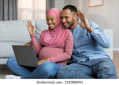 Black Muslim Spouses Expecting Baby Making Video Call With Laptop At Home, Happy Pregnant Islamic Couple Teleconferencing With Friends Or Family Via Computer, Waving Hand At Web Camera,