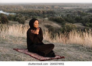 Black muslim woman praying on the carpet. Solat praying on the beautiful hill. Salah traditional pray