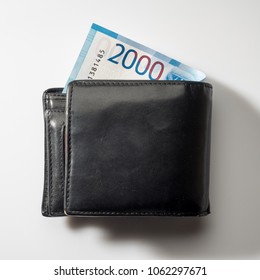 Black natural leather wallet isolated on white background. Expensive man's purse closeup. New russian ruble banknote, Two thousand rubles.