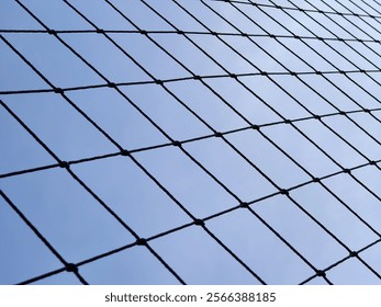 Black net with geometric patterns against a clear blue sky, perfect for backgrounds or design concepts. - Powered by Shutterstock