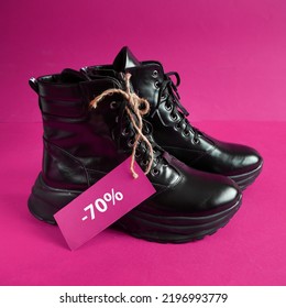 Black New Woman Or Man Rough Pair Of Boots With A Tag For The Inscription From The Sale On A Violet Background, Autumn And Winter Sale Concept