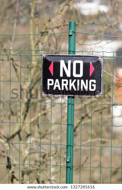 Black No\
Parking sign on green metal fence.\
Portrait.