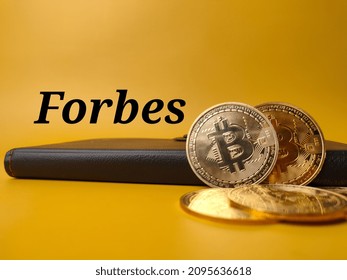 Black notebook and bitcoins with text Forbes on a yellow background.