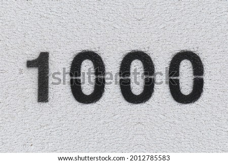 Black Number 1000 on the white wall. Spray paint. Number one thousand.