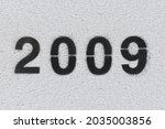 Black Number 2009 on the white wall. Spray paint. Number two thousand nine.