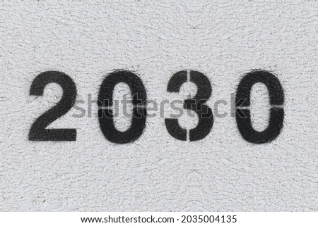 Black Number 2030 on the white wall. Spray paint. Number two thousand and thirty.