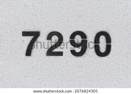 Black Number 7290 on the white wall. Spray paint. Number seven thousand two hundred and ninety.