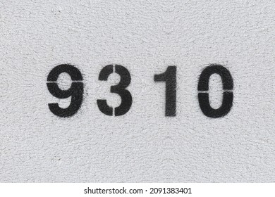 Black Number 9310 on the white wall. Spray paint. Number nine thousand three hundred and ten.