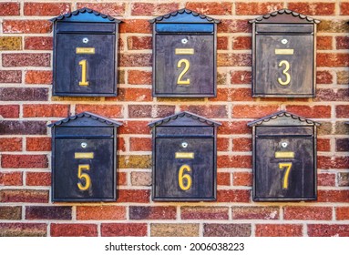 Black numbered mailboxes on brick wall at apartment building