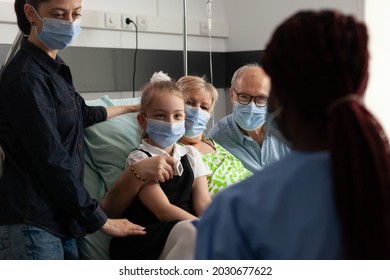 Black Nurse Checking Elderly Patient Explaining Disease Treatment During Clinical Therapy In Hospital Ward. Caring Family With Medical Face Mask Against Covid19 Supporting Senior Woman Patient
