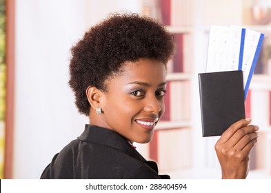 Black office woman with her back to lens and head turned towards camera holding up passport document concept transport airplane airline bus train traveling airport 