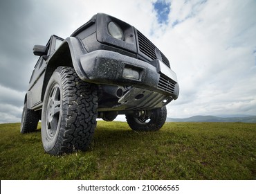 A black offroad all terrain vehicle on a green pasture in the mountains