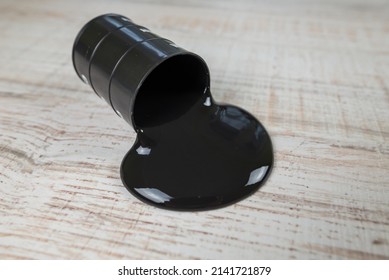 Black Oil Pouring Out Of A Barrel On A Wooden Background