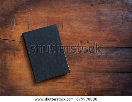 Black old closed book on wooden table. Top view, copy space
