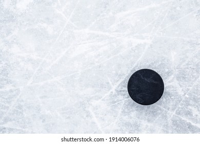 Black old rubber puck on ice background. Closeup. Empty place for text. 