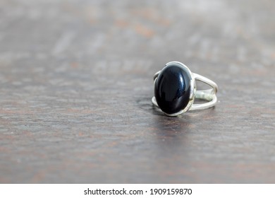 Black Onyx Ring On Blurred Wooden Background 