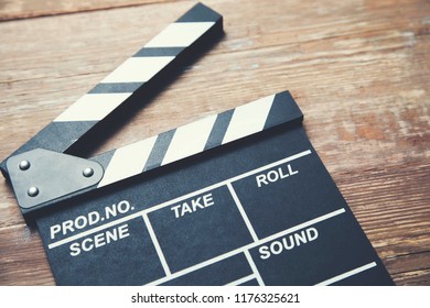 Black open clapper board isolated on wooden background