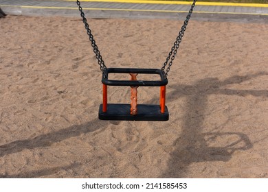 Black And Orange Baby Swing At A Playground.