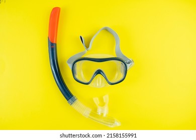Black orange colored swimming goggles isolated on yellow background, summer idea, holiday preparation concept with protective goggles, swimming equipment, top view 