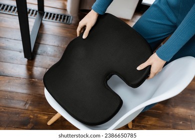 Black orthopedic pillow for correct posture while sitting on a chair at a table, corrective chair cushion. High quality photo