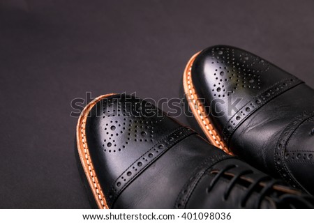 black oxford shoes with shoelace on black background closeup, top view 