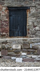 A Black Painted Door Within A Granite Wall