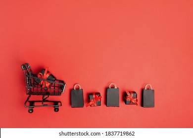 black paper bags and gift boxes with shopping cart on red background, copy space. black friday concept - Powered by Shutterstock